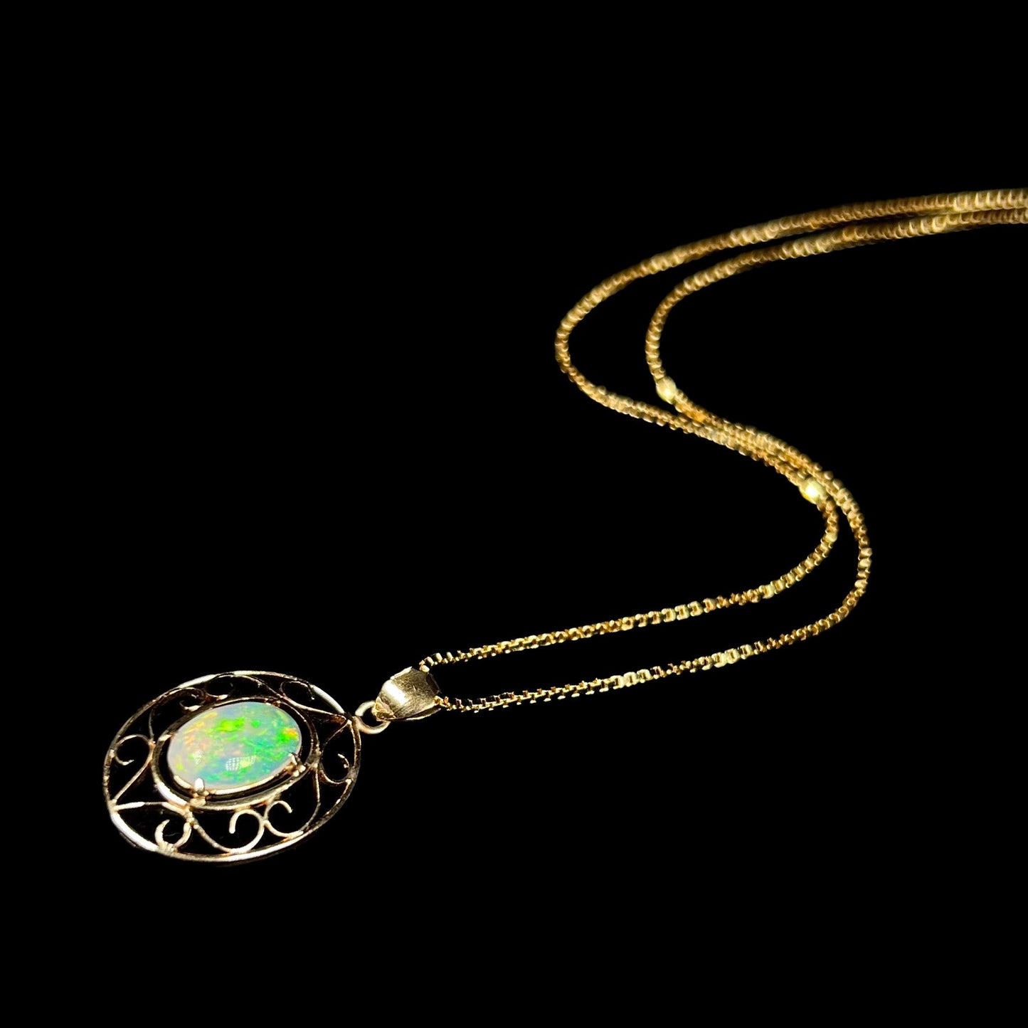 An 18 karat yellow gold filigree opal necklace. The opal has bright green color play.