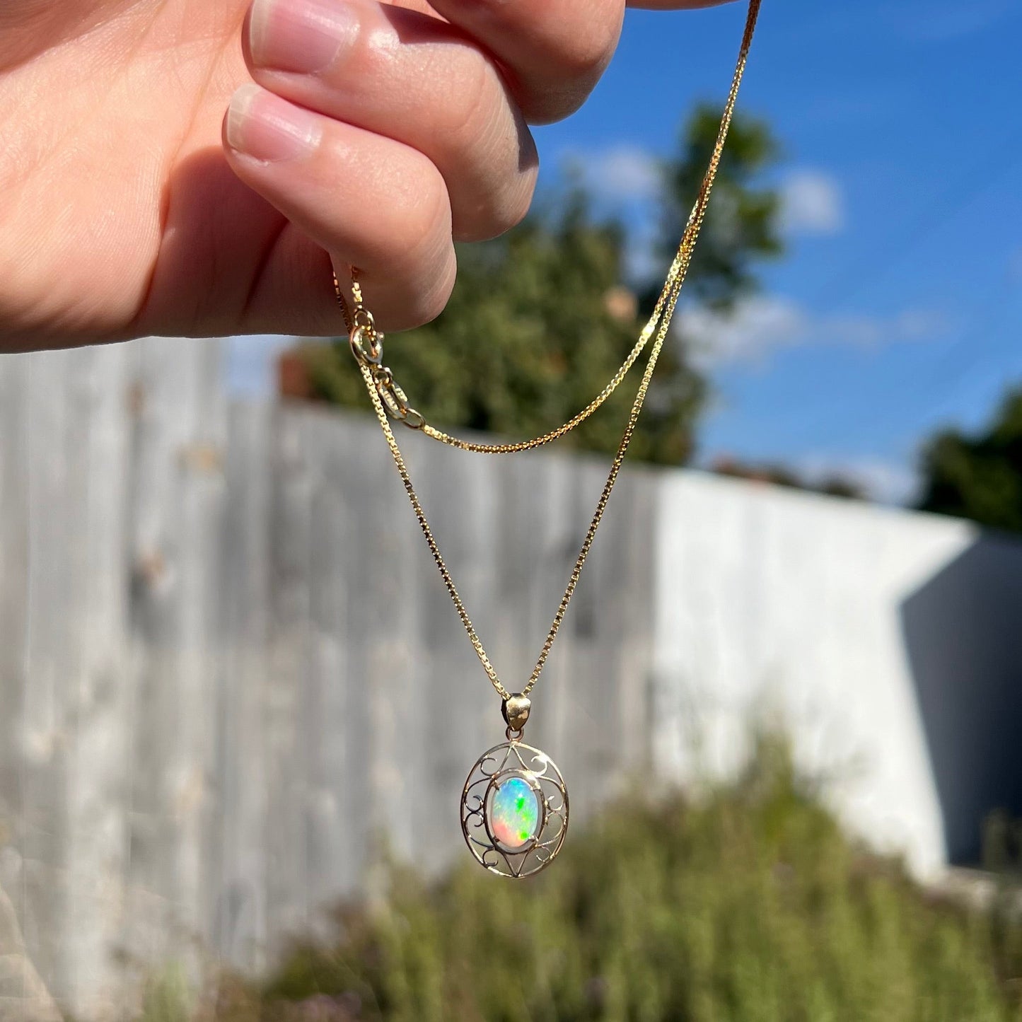 An 18 karat yellow gold filigree necklace set with a green, oval cut Australian crystal opal.