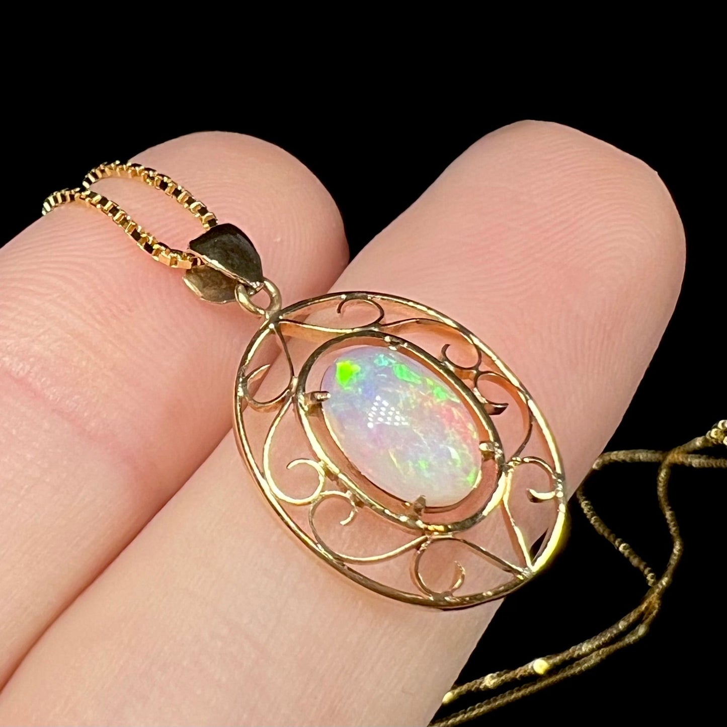 An 18 karat yellow gold filigree opal necklace. The opal has bright green color play.