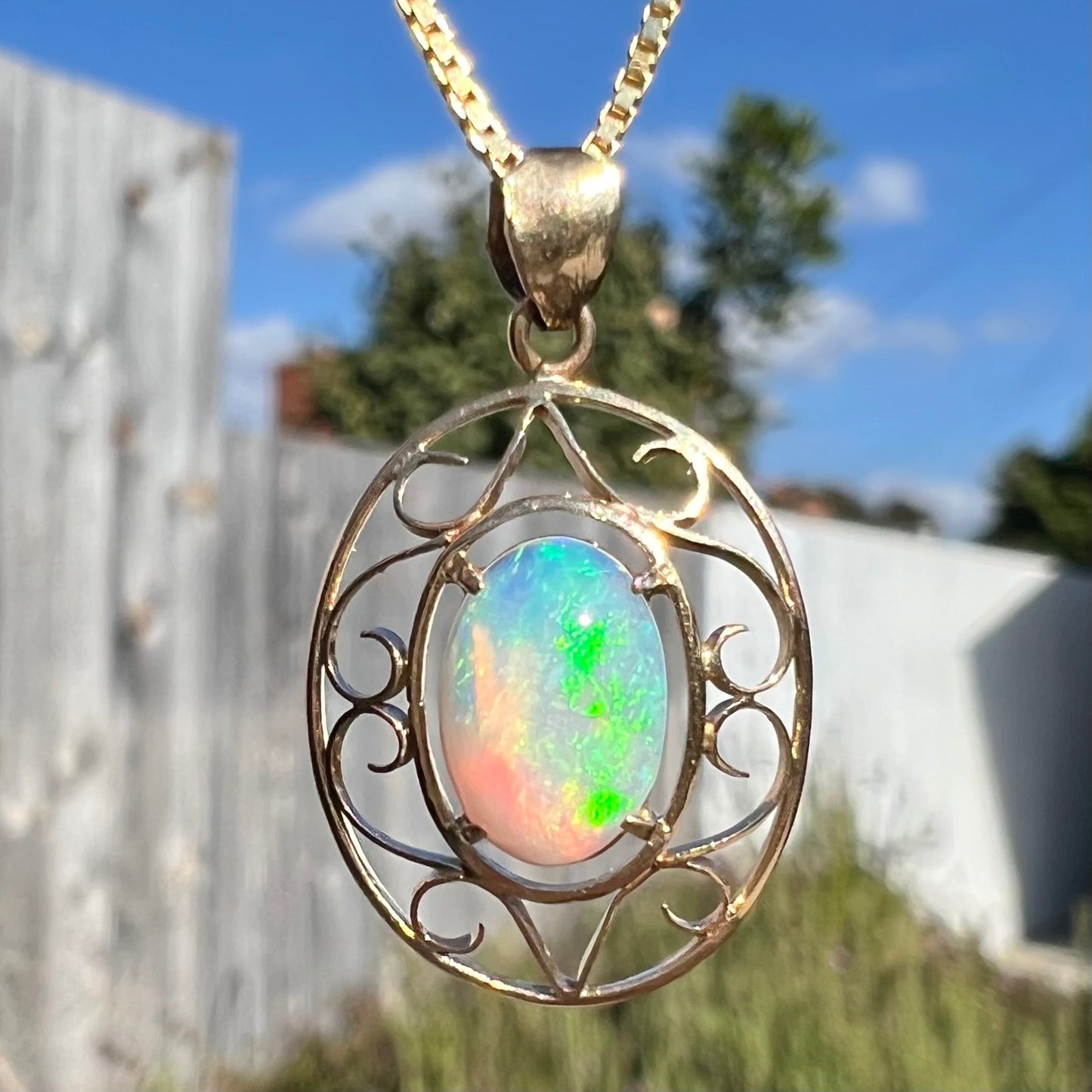 An 18 karat yellow gold filigree necklace set with a green, oval cut Australian crystal opal.
