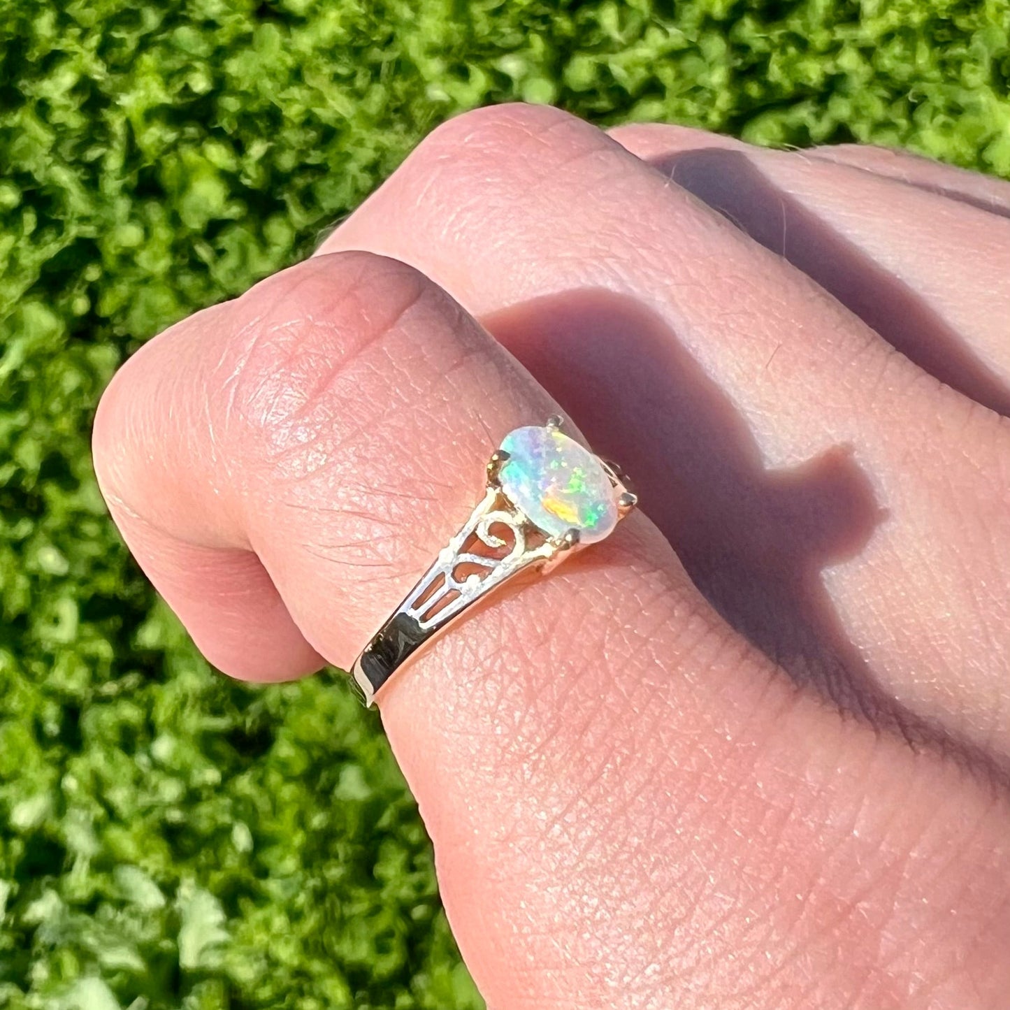 A ladies' natural opal in gold filigree ring. The opal shines with colors of green and blue.