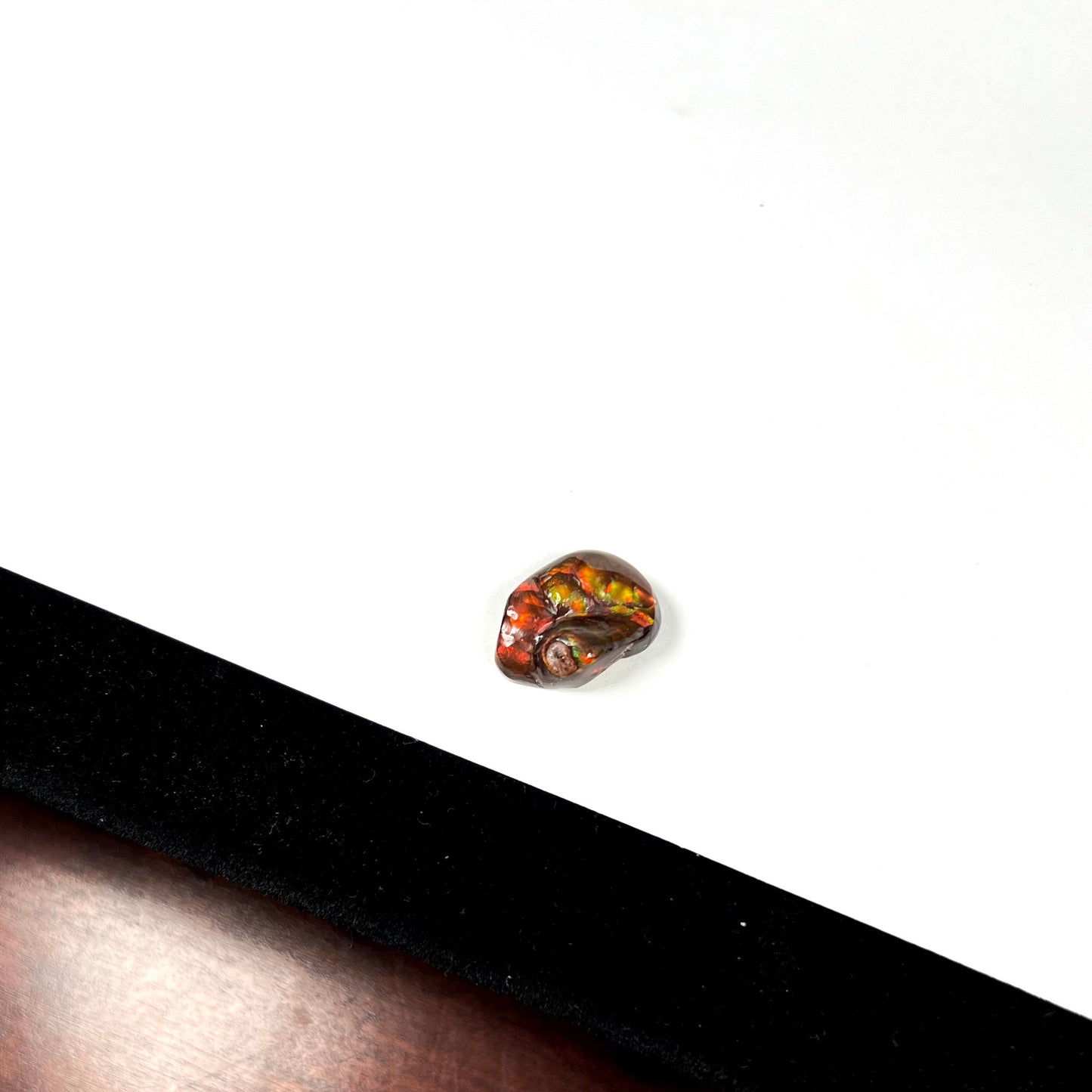 A large Mexican fire agate gemstone. The stone is red with green iridescence and a waxy luster.