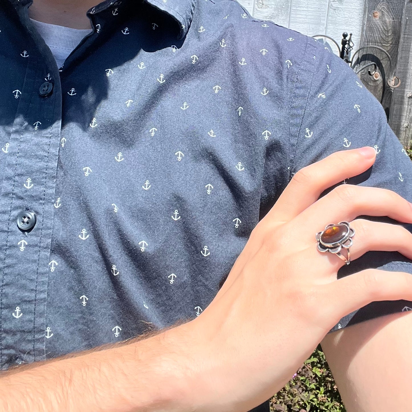 Fire agate ring worn across shoulder, stone appears deep brown in light.