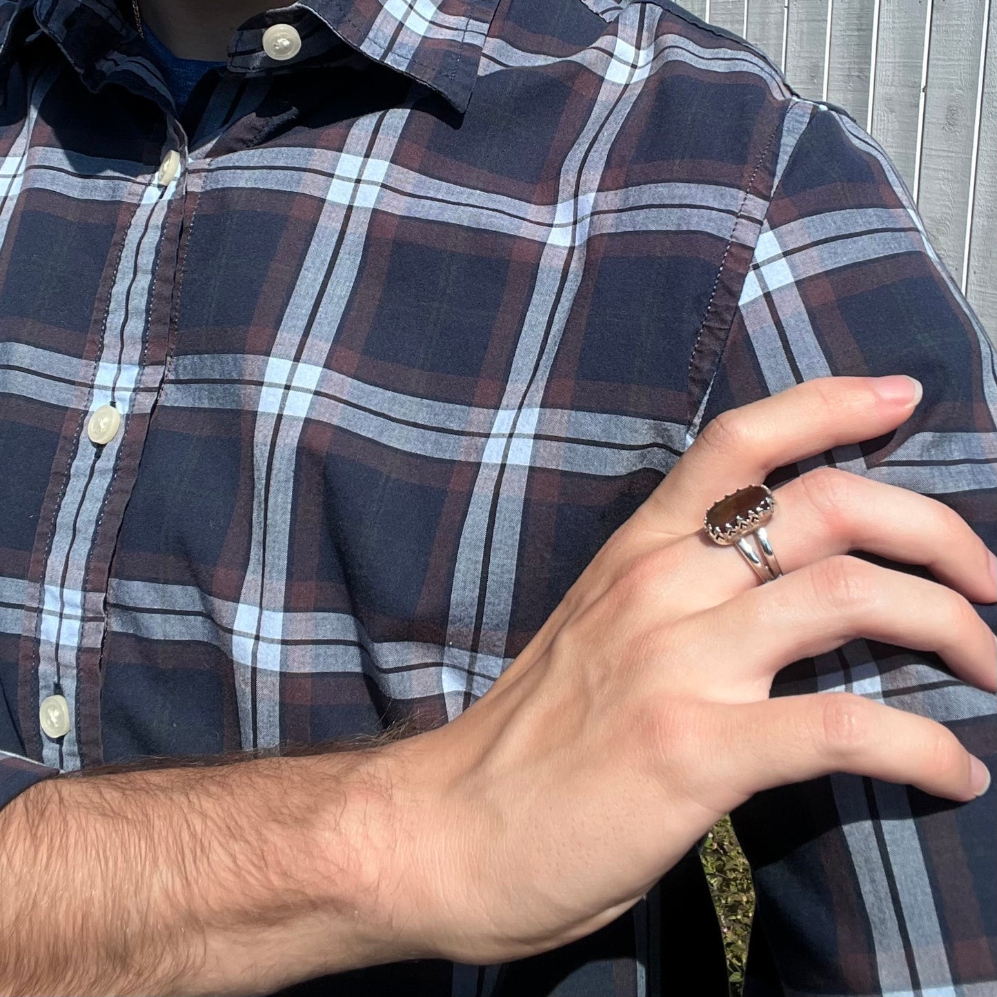 A fire agate ring with a silver crown design, worn on a hand as it rests on a model's shoulder.