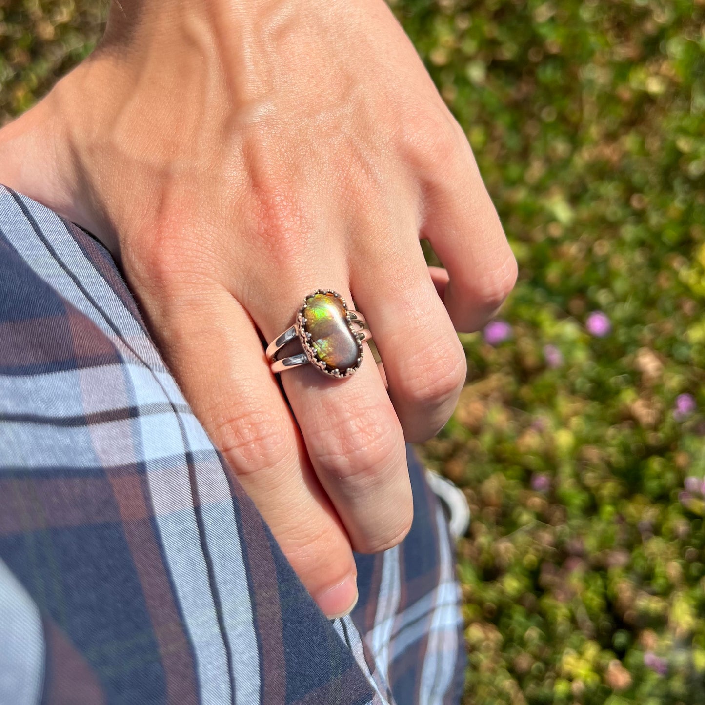 Green fire agate ring worn on a hand in the sunlight, resting on the model's hip.