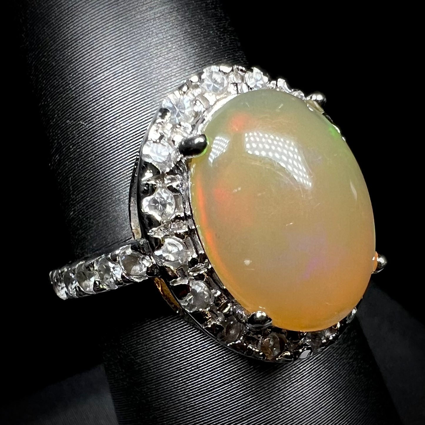 A sterling silver Ethiopian fire opal ring with a CZ halo shown from an angled view.