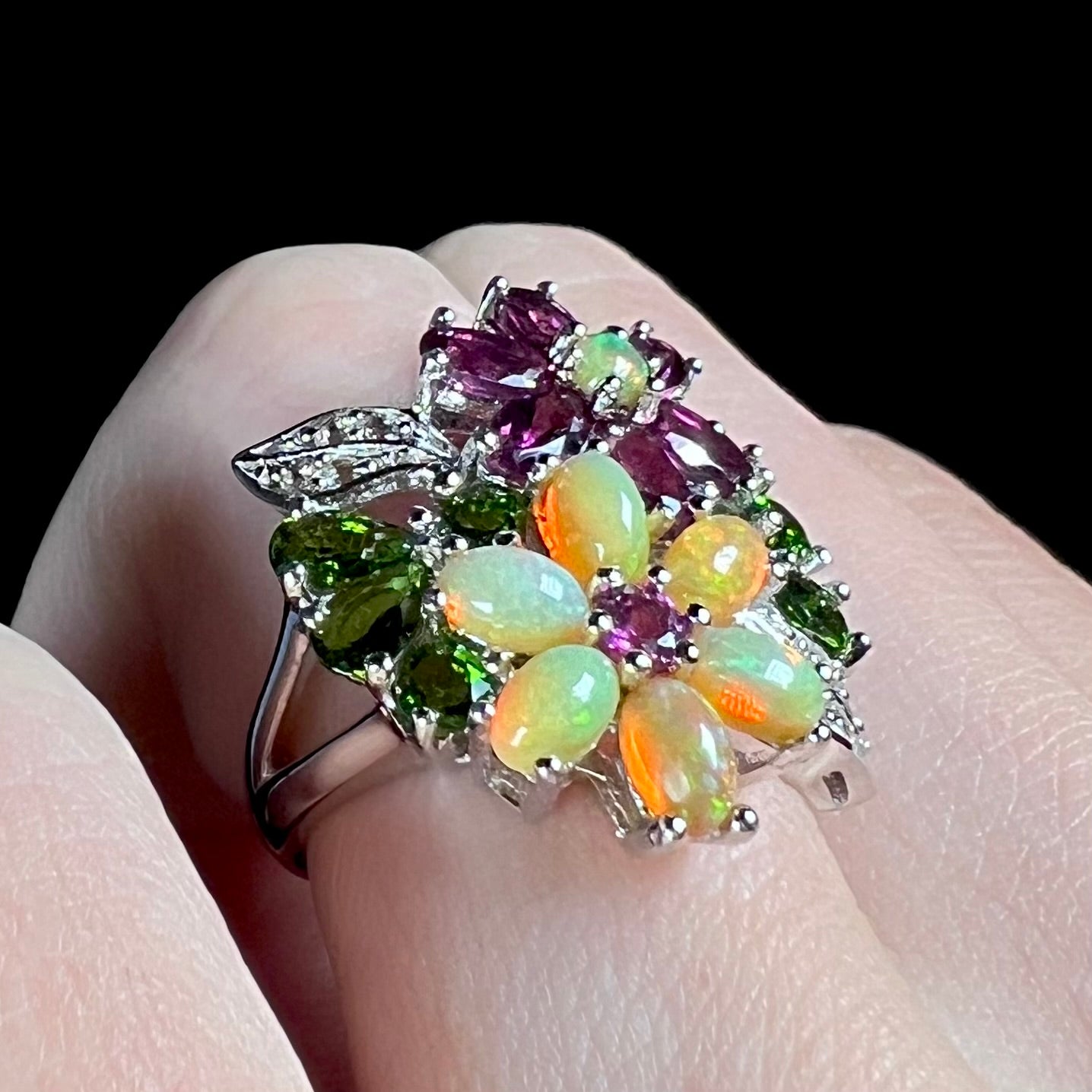 A sterling silver fire opal flower ring, shown at an angle while worn on a finger.