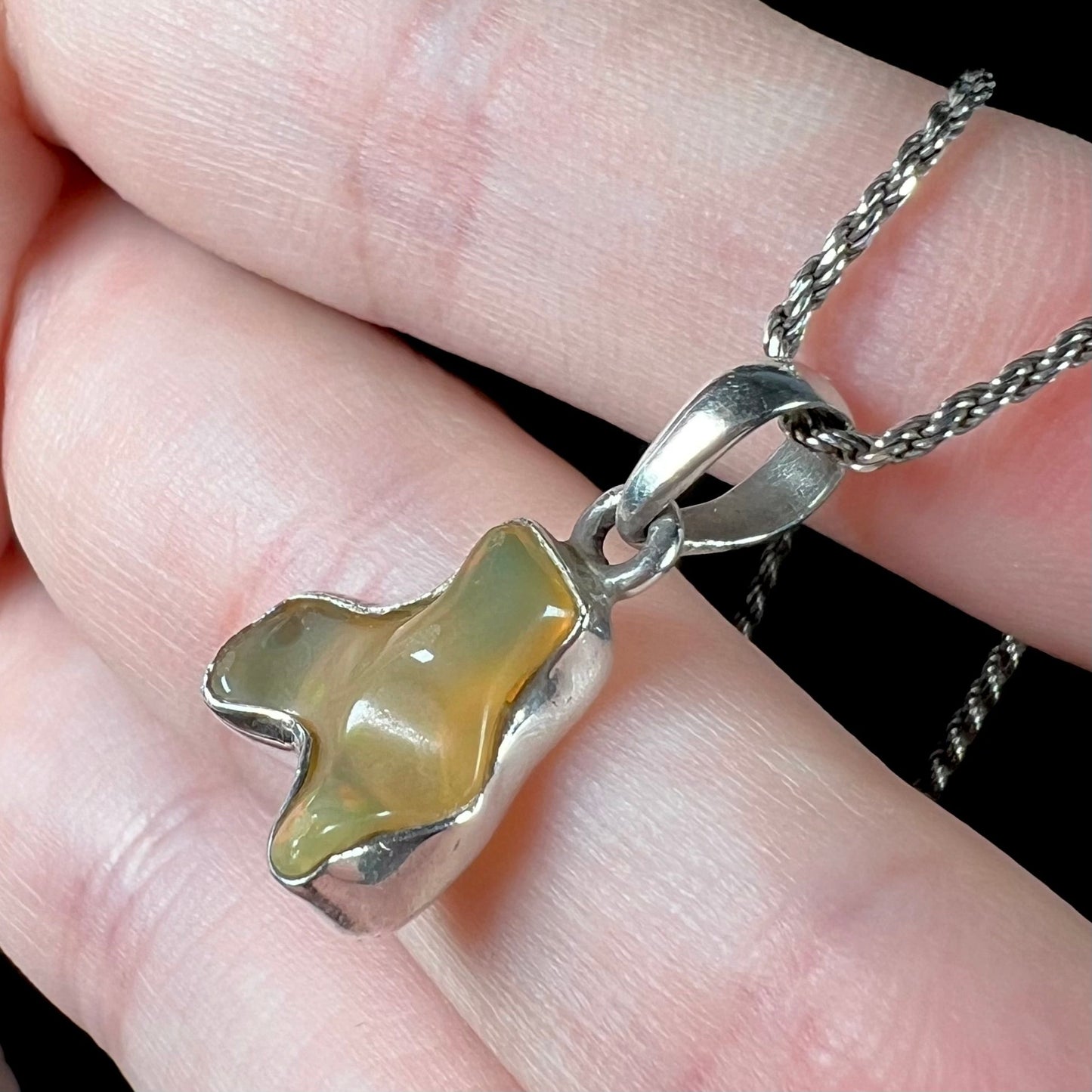 A freeform shaped Mexican fire opal necklace on a sterling silver rope chain.