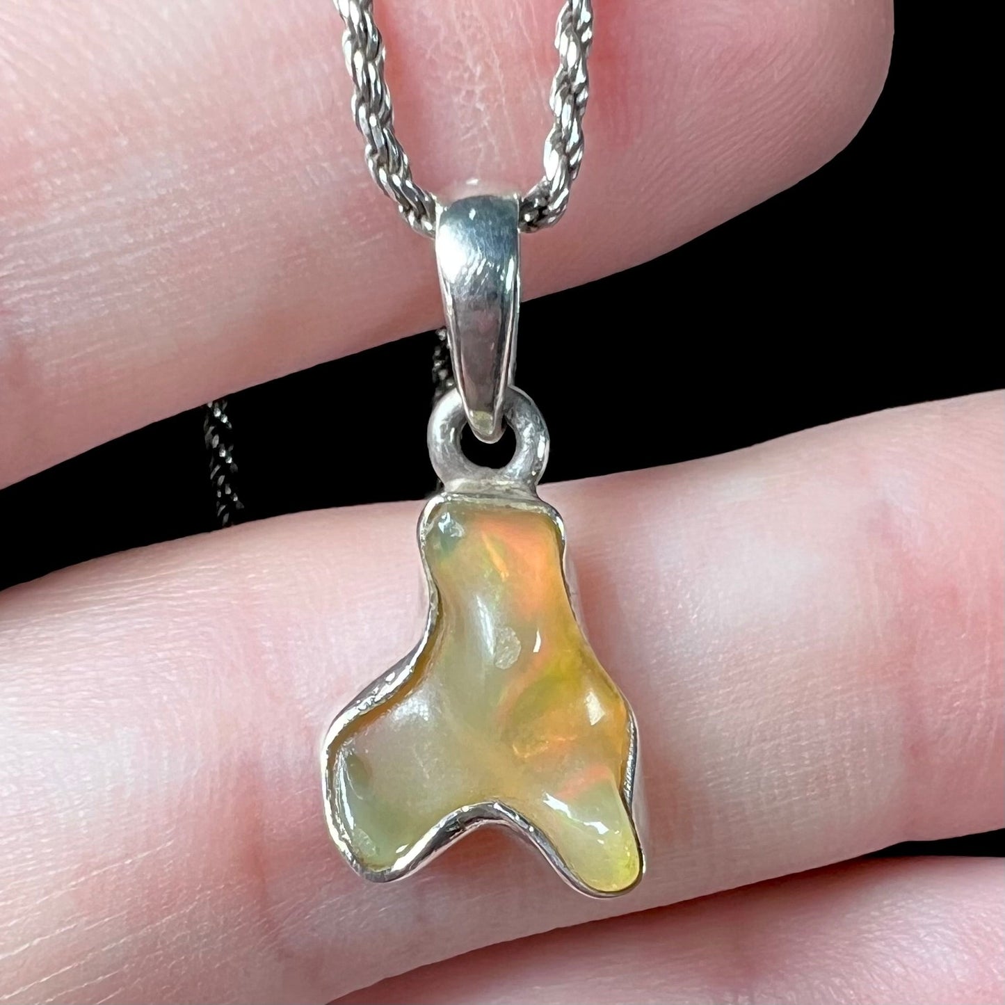 A freeform shaped Mexican fire opal necklace on a sterling silver rope chain.
