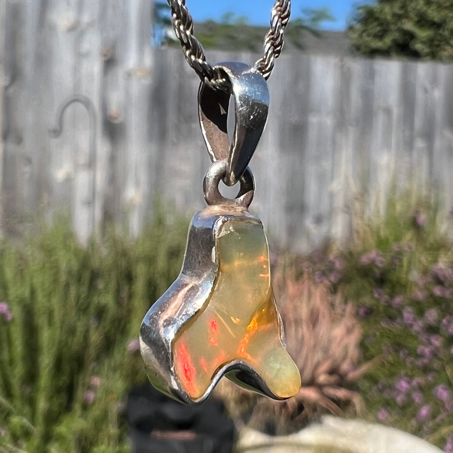 A freeform shaped Mexican fire opal necklace on a sterling silver rope chain.