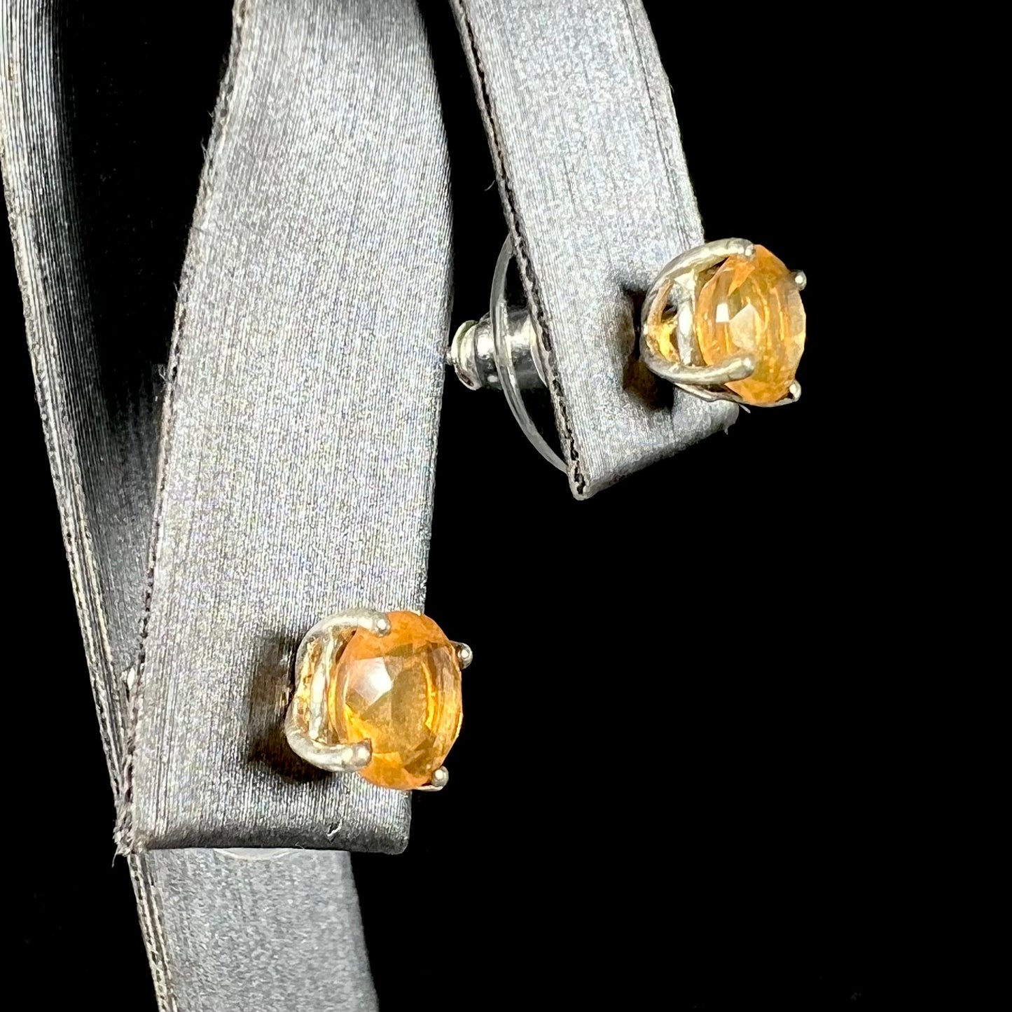 A pair of Mexican fire opal stud earrings in sterling silver shown at an angle.