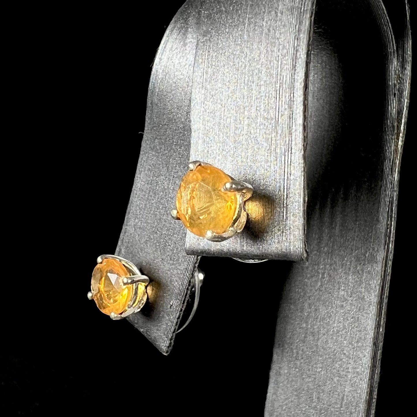 A pair of Mexican fire opal stud earrings in sterling silver shown at an angle.