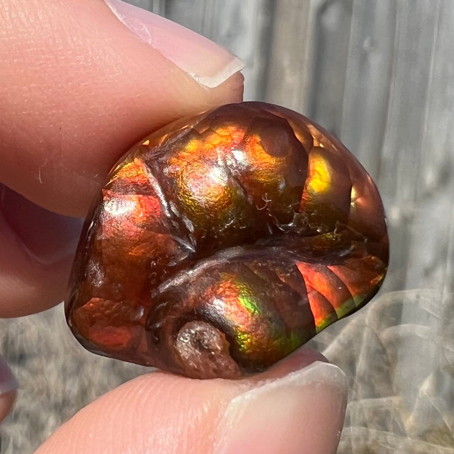 A large Mexican fire agate gemstone. The stone is red with green iridescence and a waxy luster.