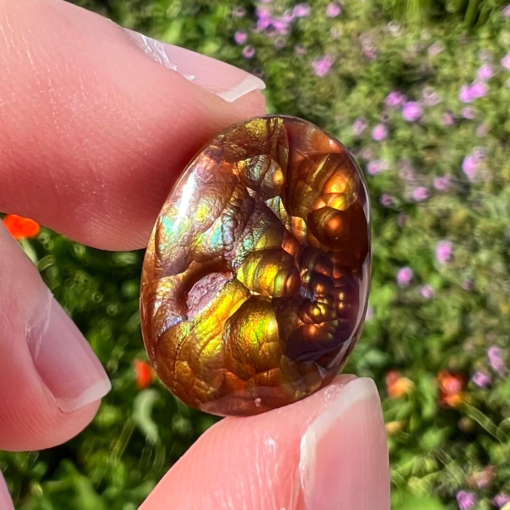 A loose, oval cabochon cut fire agate gemstone.  The stone is bubbly green with blue overtones.