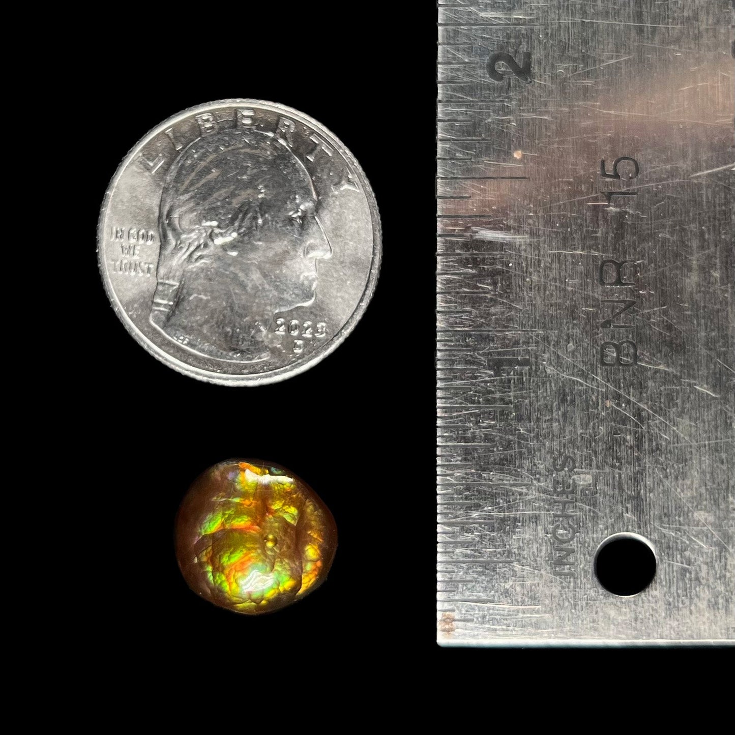 An iridescent green, yellow, and red Mexican fire agate stone. The stone is an off-round cabochon.