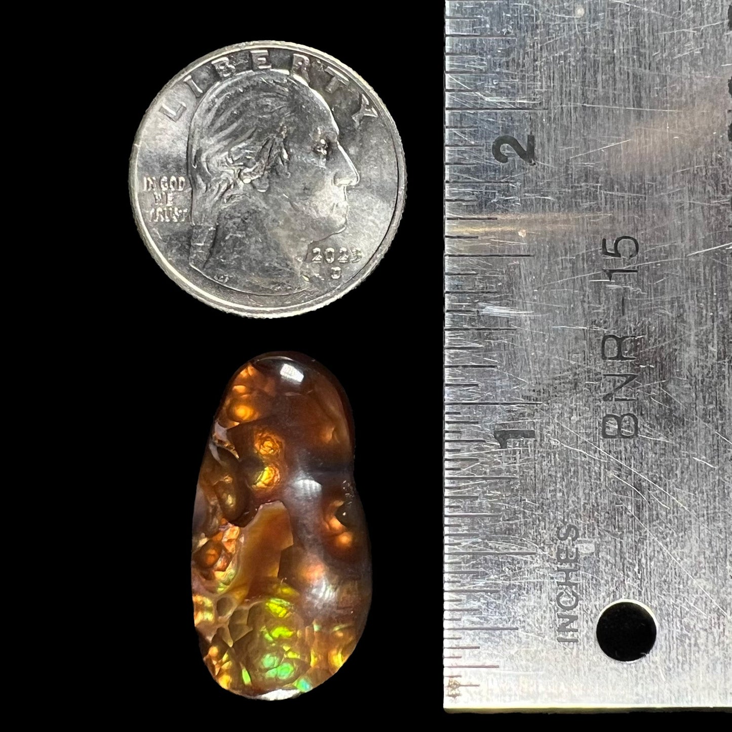 A loose fire agate cabochon. The stone has iridescent green, yellow, and blue colors.