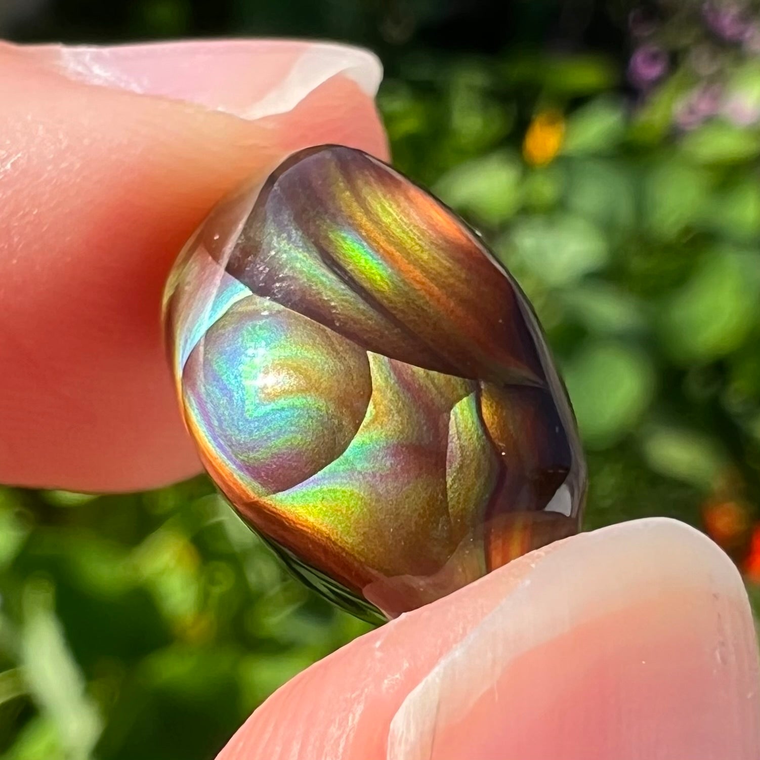 An oval cabochon cut Mexican fire agate stone.  The stone has bright, multicolored iridescent banding.