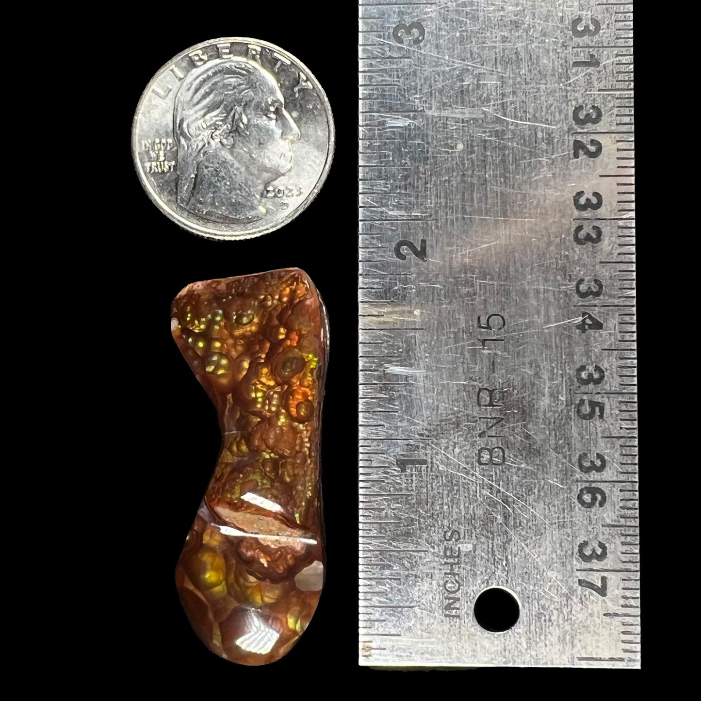 A loose, freeform cabochon cut fire agate gemstone. The stone exhibits a bubbly pattern.