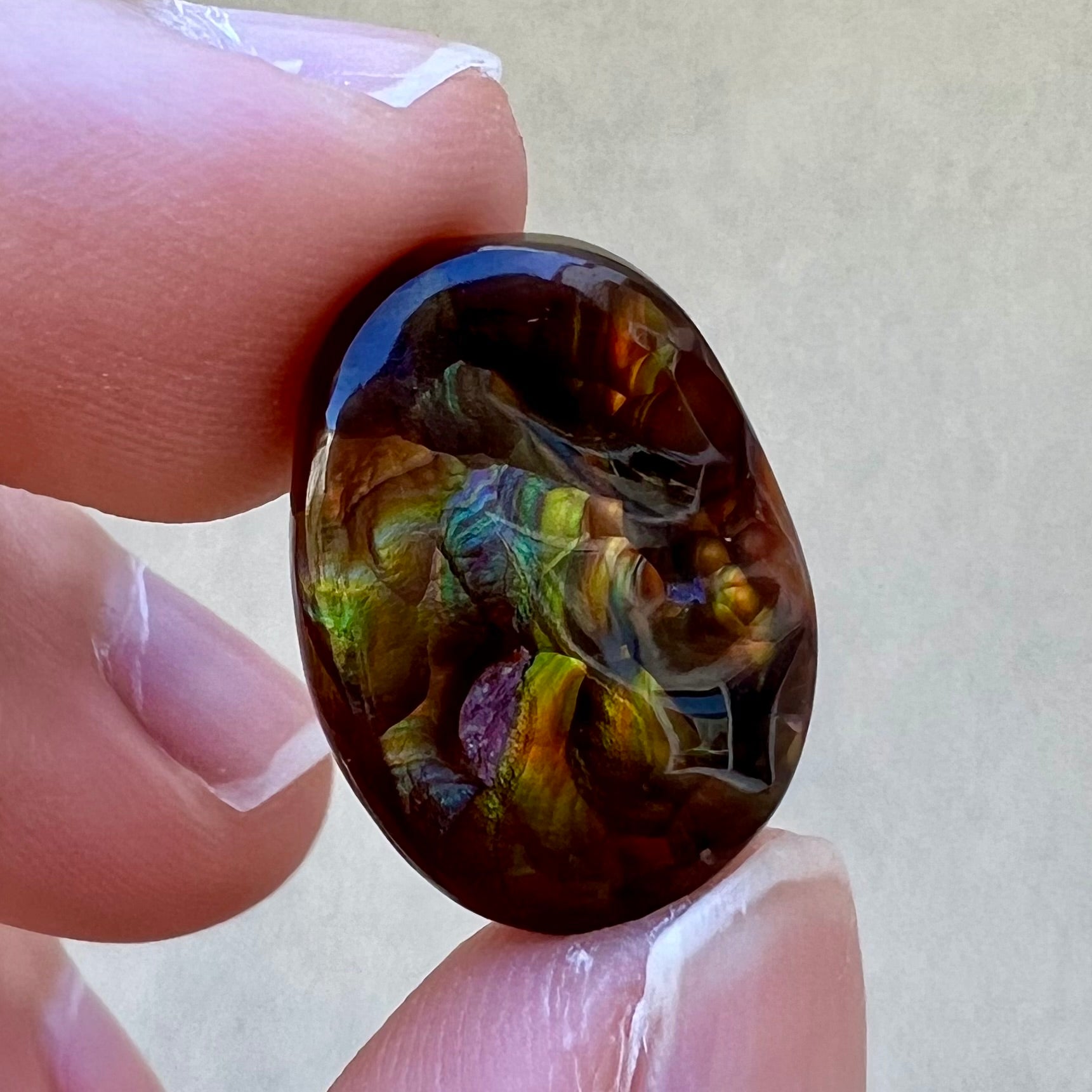 A loose, oval cabochon cut fire agate gemstone.  The stone is bubbly green with blue overtones.