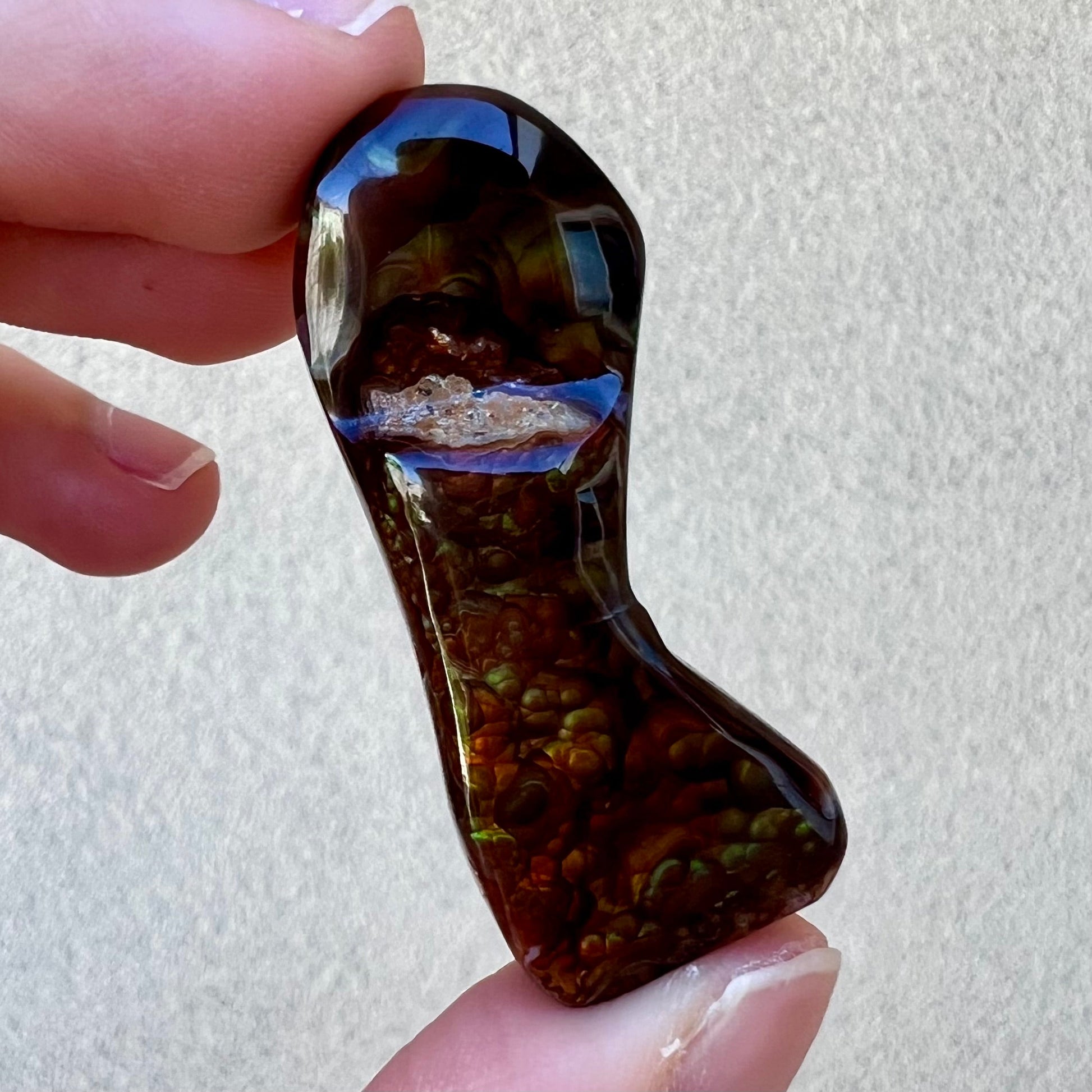 A loose, freeform cabochon cut fire agate gemstone.  The stone exhibits a bubbly pattern.