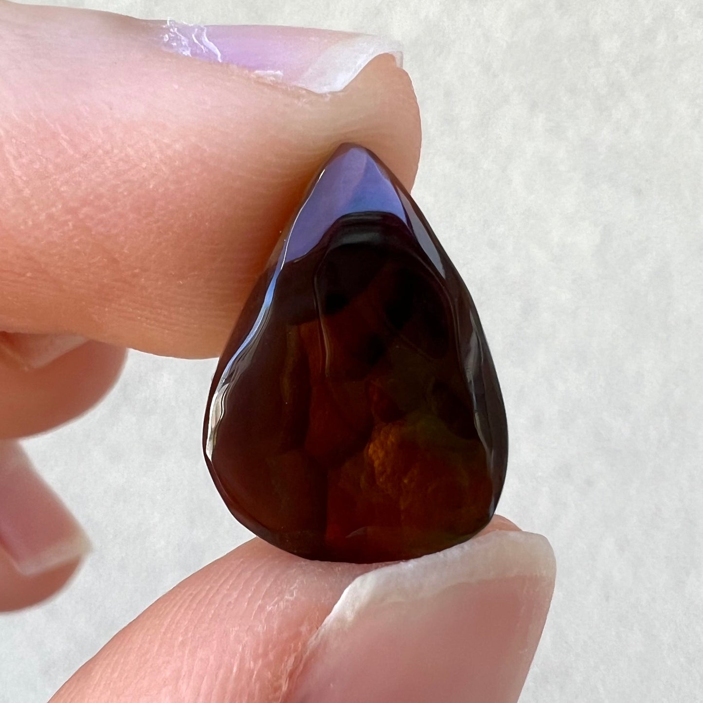A loose, pear shaped Mexican fire agate gemstone. The stone is predominantly vivid red with green overtones.