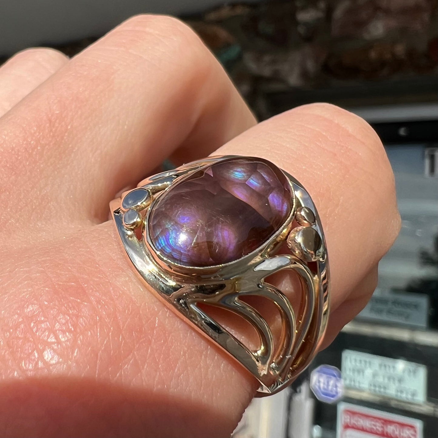 An oval cabochon cut fire agate with purple and blue colors set in a yellow gold men's ring.