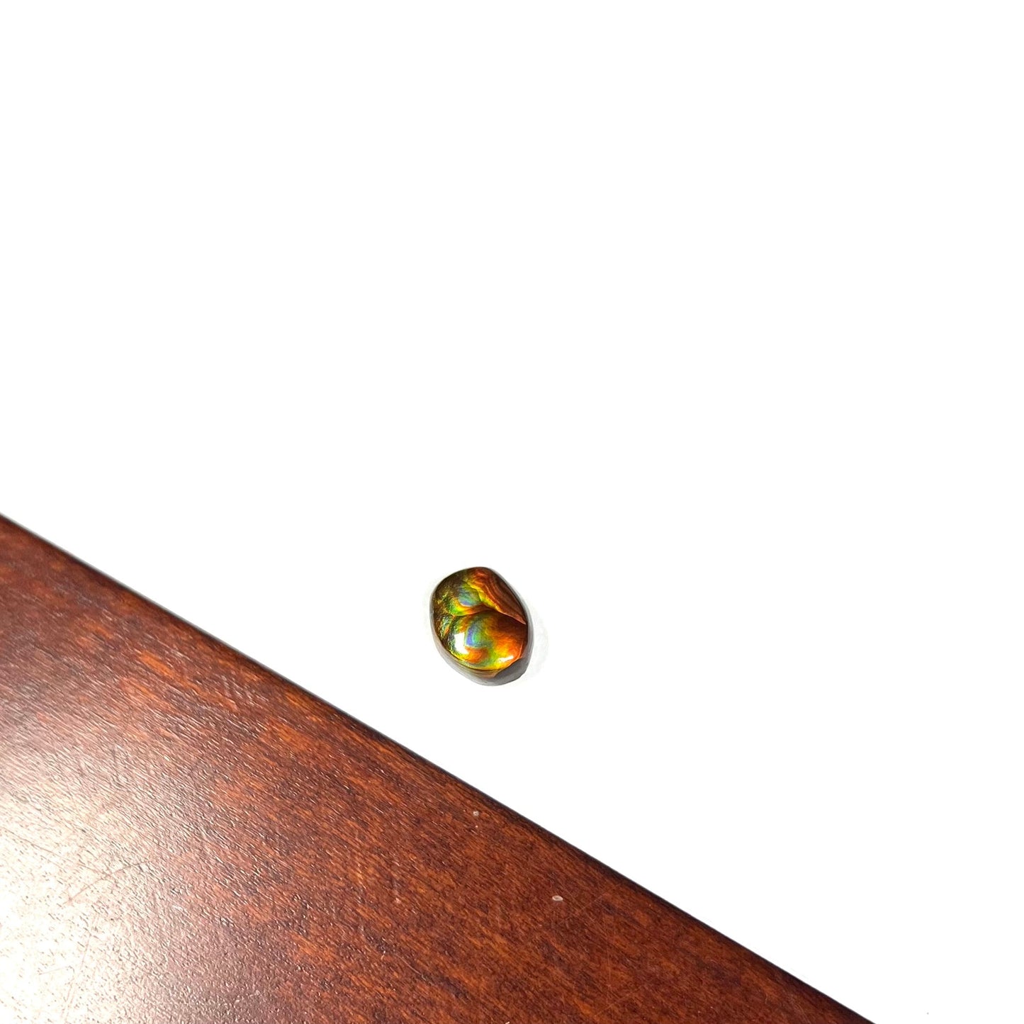 A loose, imperial grade Mexican fire agate gemstone. The stone brightly glows every color in the sunlight.
