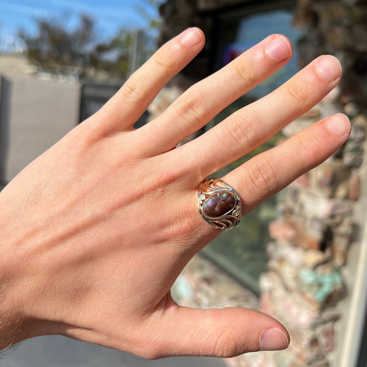 An oval cabochon cut fire agate with purple and blue colors set in a yellow gold men's ring.