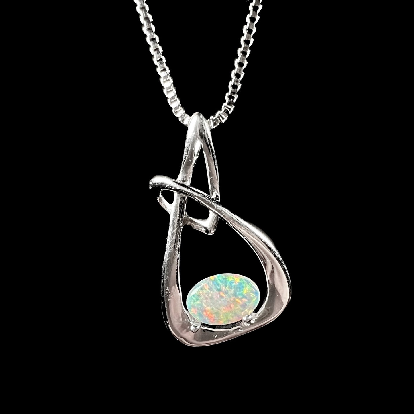 A ladies' sterling silver pendant set with an oval cabochon cut natural white crystal opal.