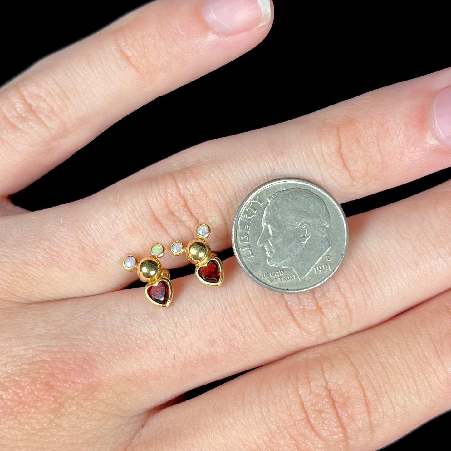 A pair of 18 karat yellow gold stud earrings set with two round fire opals and heart shaped garnets.