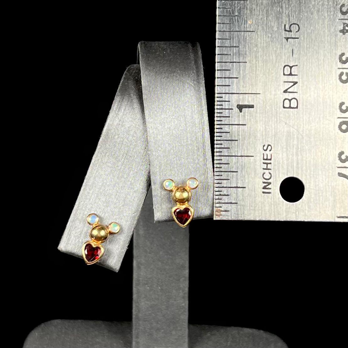 A pair of 18 karat yellow gold stud earrings set with two round fire opals and heart shaped garnets.