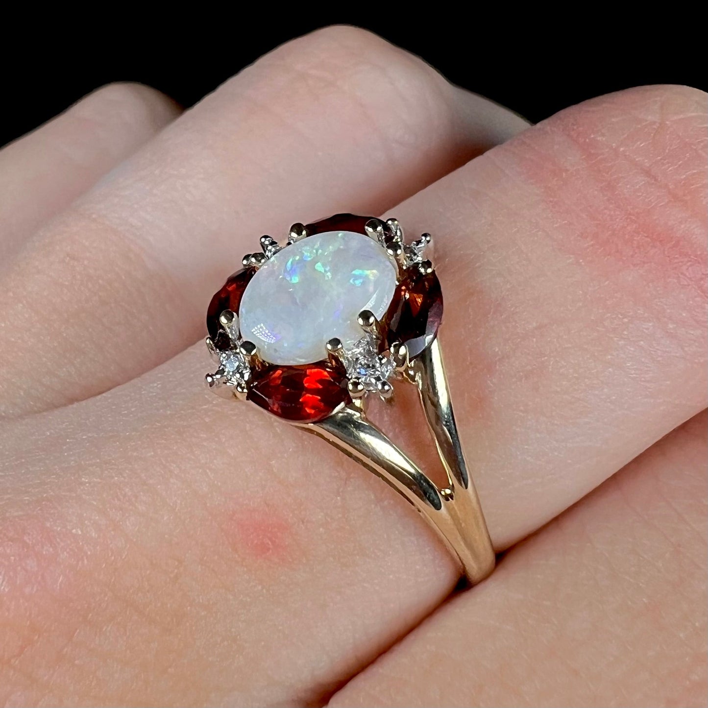 A ladies natural opal ring in yellow gold. The opal is surrounded by red marquise cut garnets and diamonds.