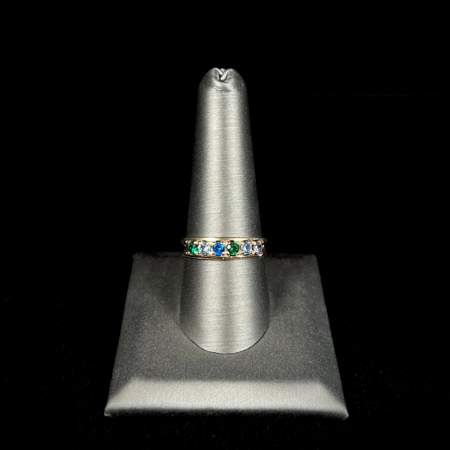 A ladies' yellow gold band set with green, dark blue, light blue, and light purple stones.