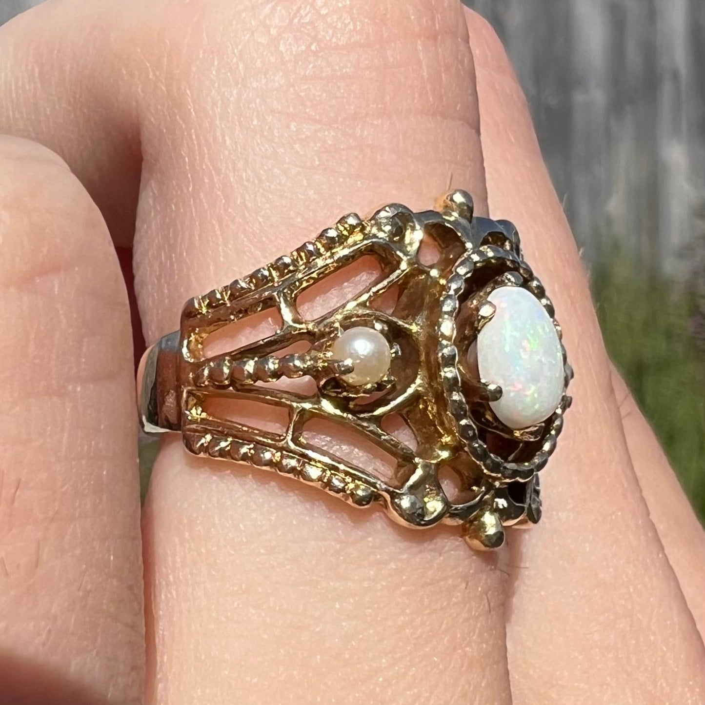 A Victorian-style yellow gold opal ring mounted with two seed pearl accents.