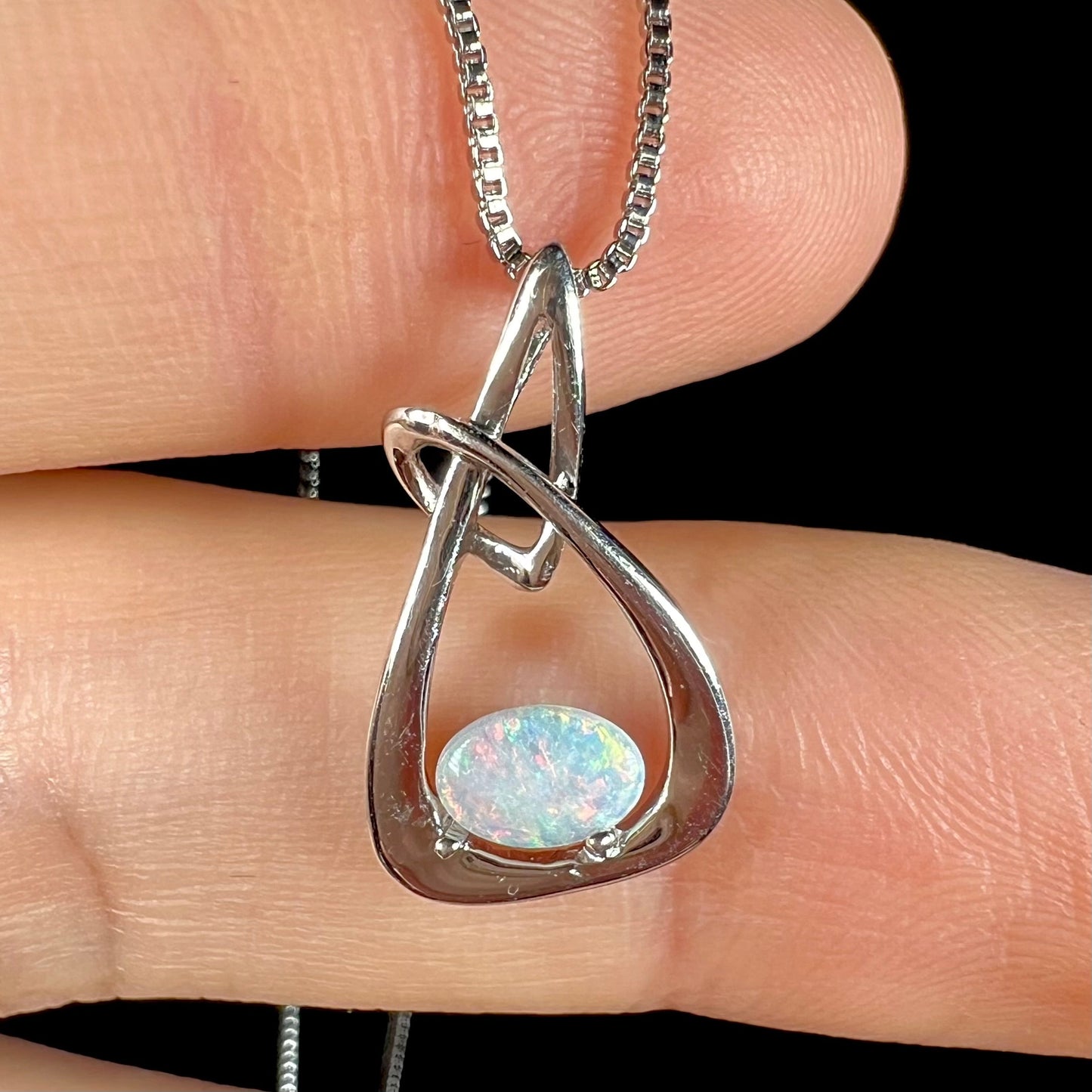 A ladies' sterling silver pendant set with an oval cabochon cut natural white crystal opal.