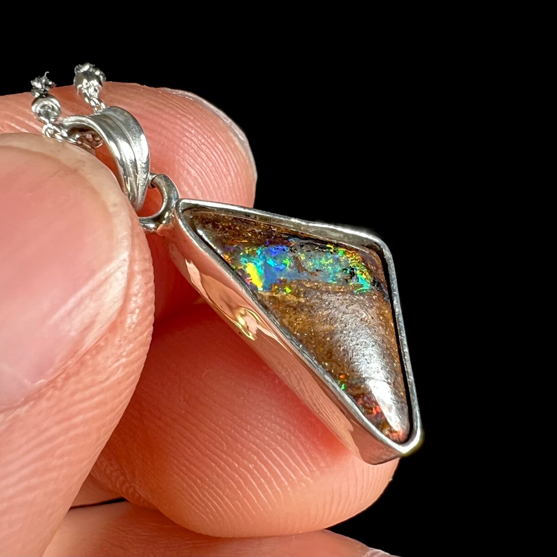 A triangle shaped opal necklace in sterling silver.  The opal shines with every color of the rainbow.