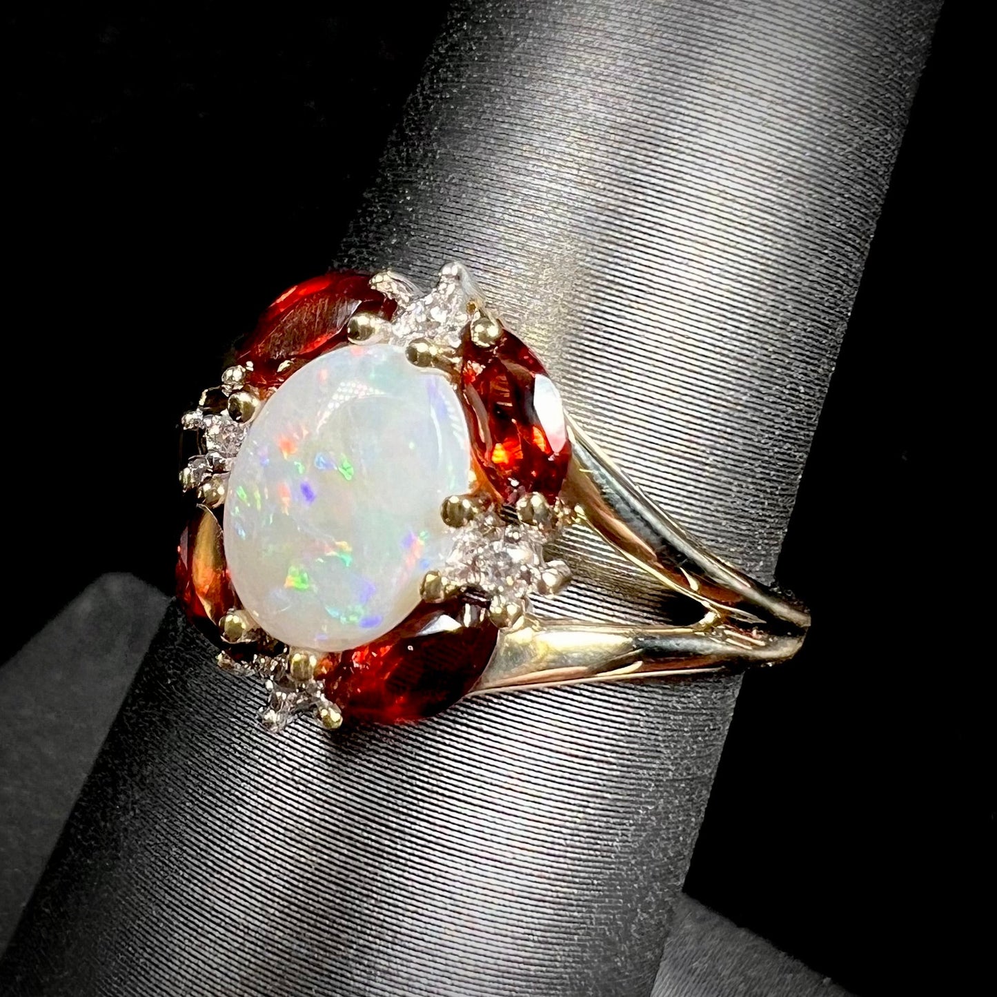 A ladies natural opal ring in yellow gold. The opal is surrounded by red marquise cut garnets and diamonds.