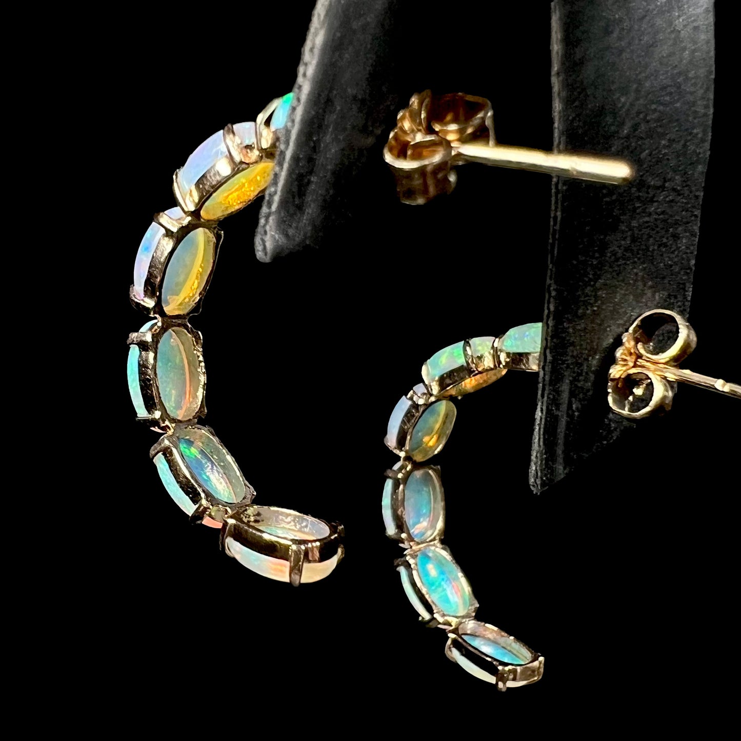 Back view of opal semi-hoop earrings showing open-back gold setting and push backs.