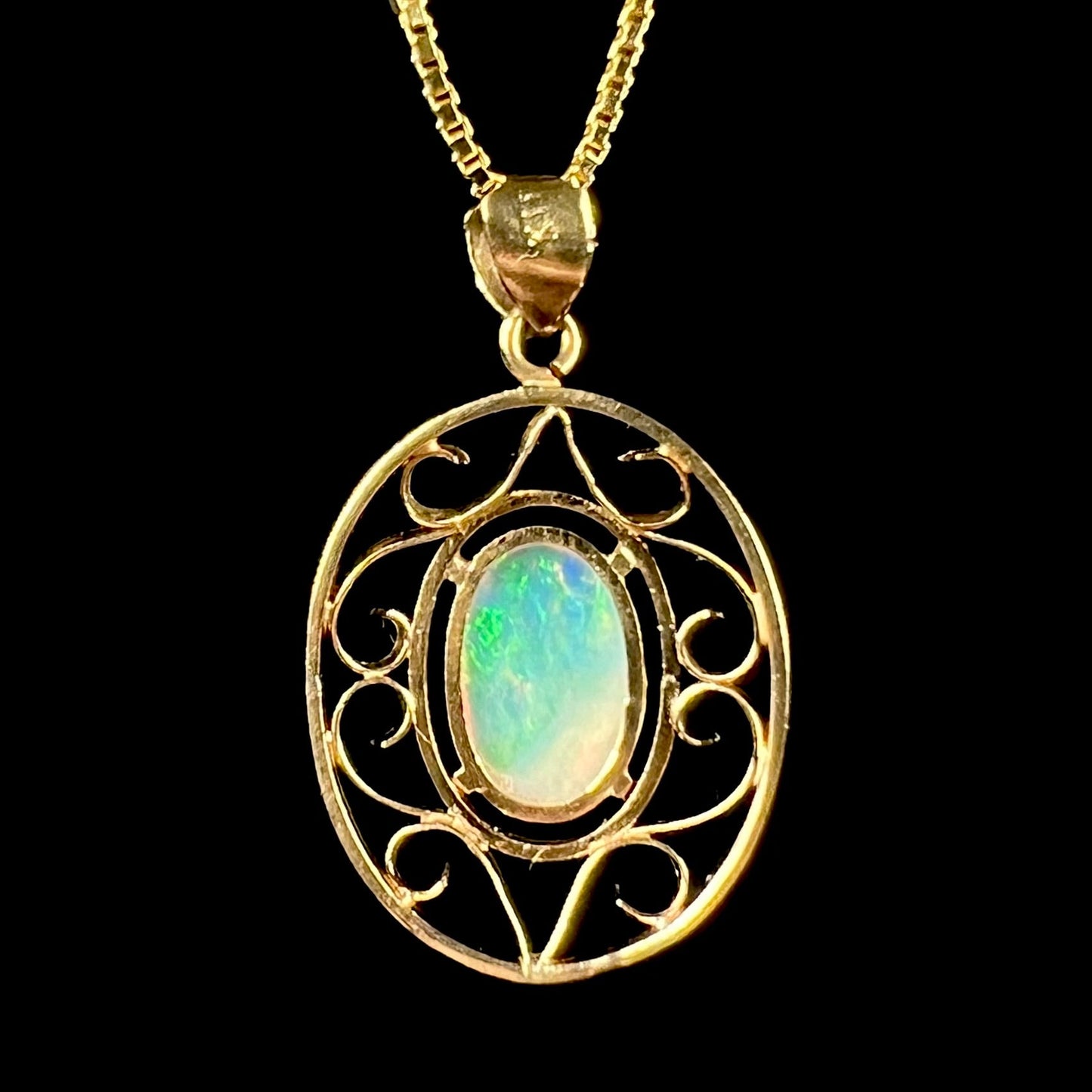 An 18 karat yellow gold filigree opal necklace. The opal has bright green color play.
