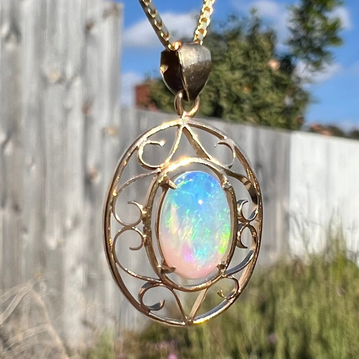 An 18 karat yellow gold filigree necklace set with a green, oval cut Australian crystal opal.