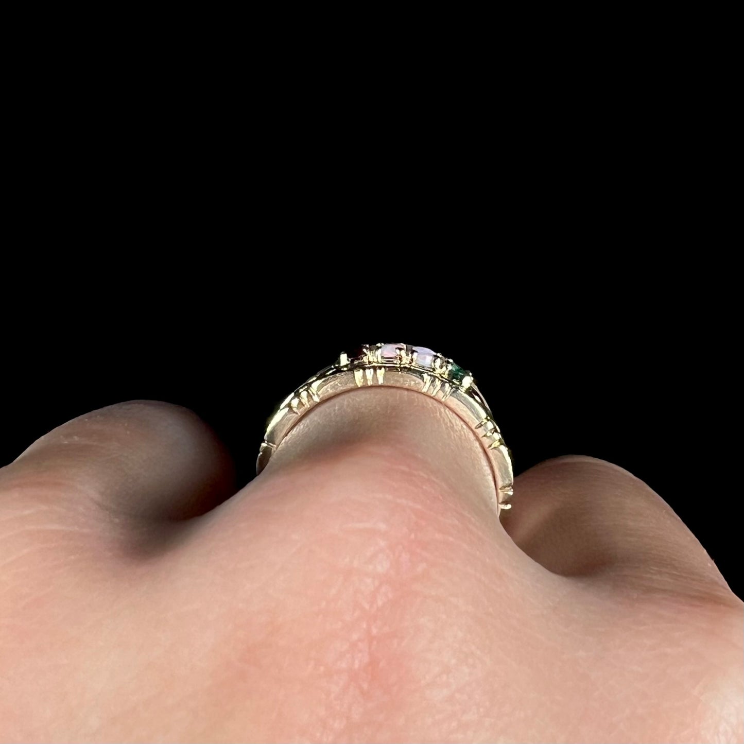 Side profile gallery view of a gold mother's ring, worn on a finger.
