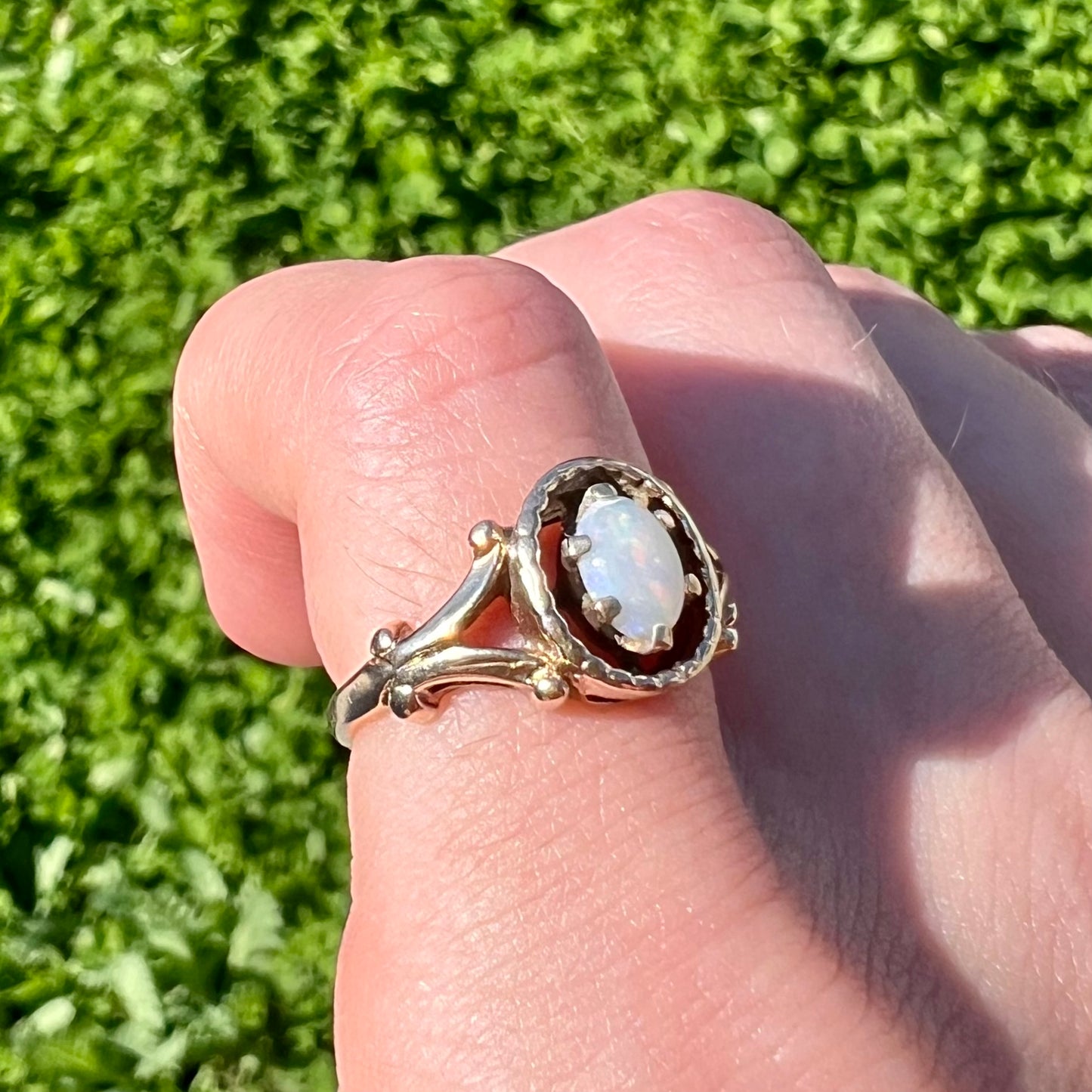 A ladies' Art Nouveau style opal solitaire ring. The mounting is yellow gold with filigree accents.