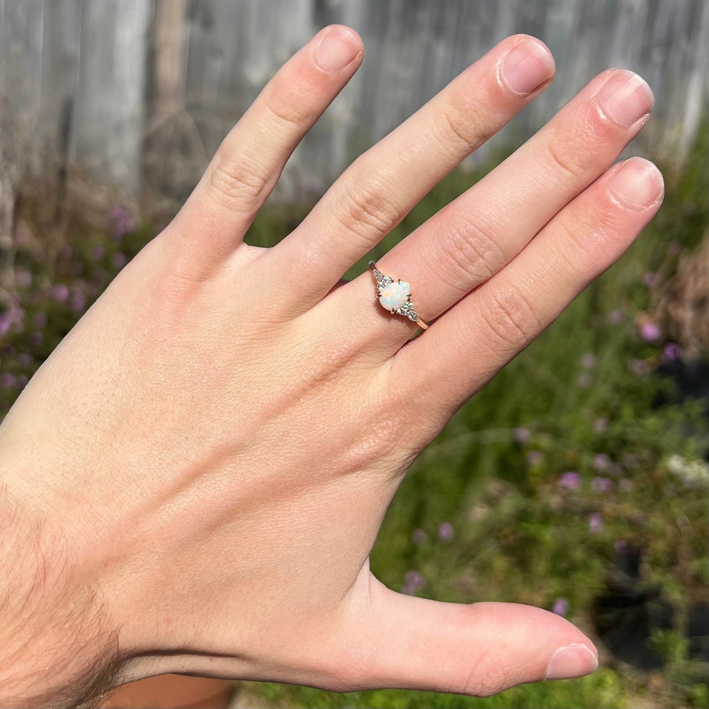 A dainty, pear shaped opal ring mounted in yellow gold with moissanite accents.
