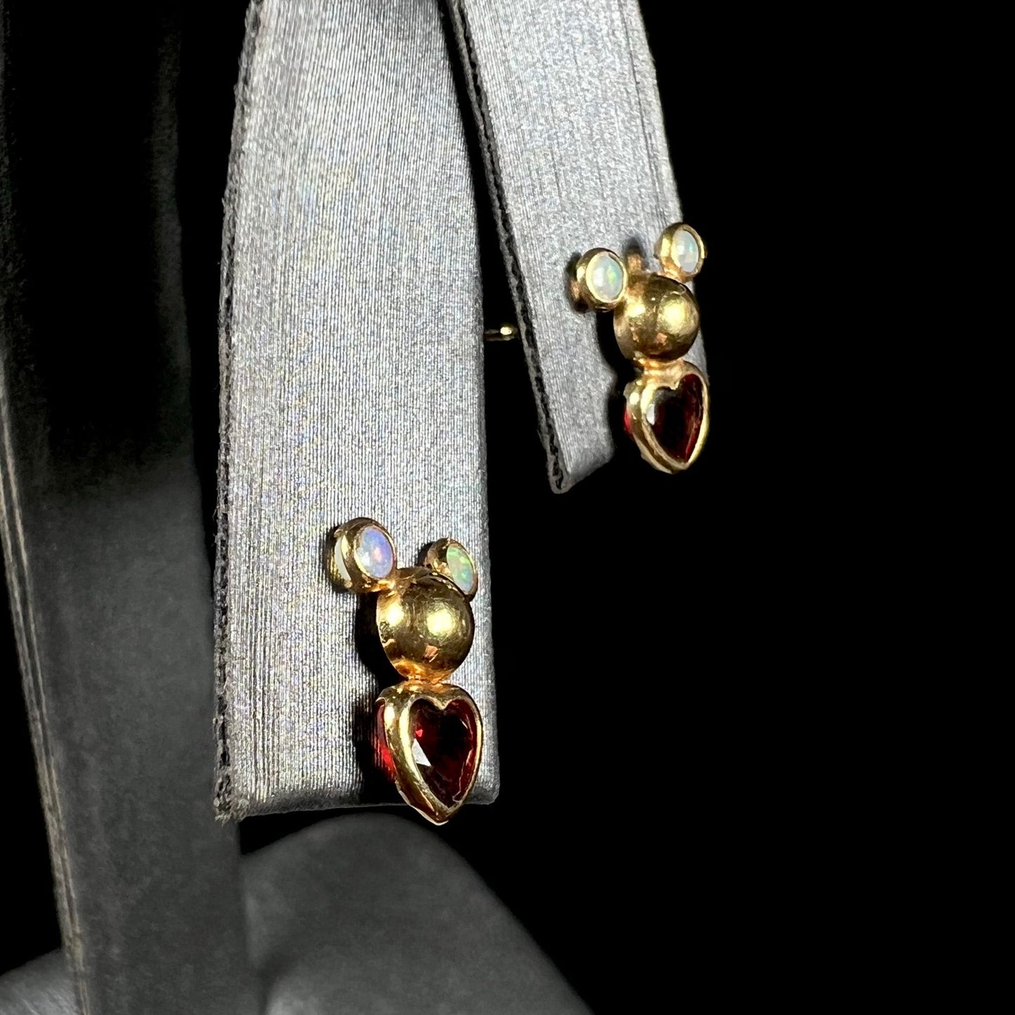 A pair of 18 karat yellow gold stud earrings set with two round fire opals and heart shaped garnets.
