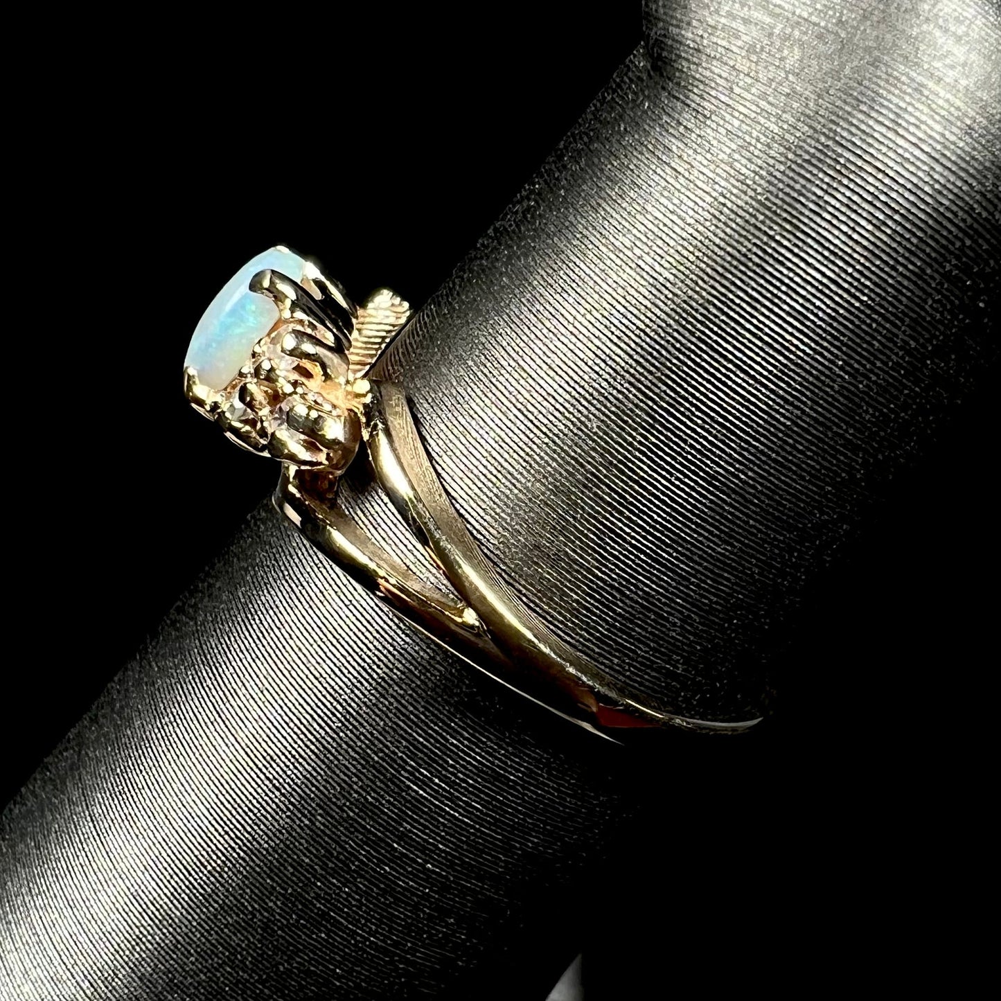 A ladies' yellow gold opal and diamond pinkie ring. The ring is a small size, and the opal shines green and blue colors.