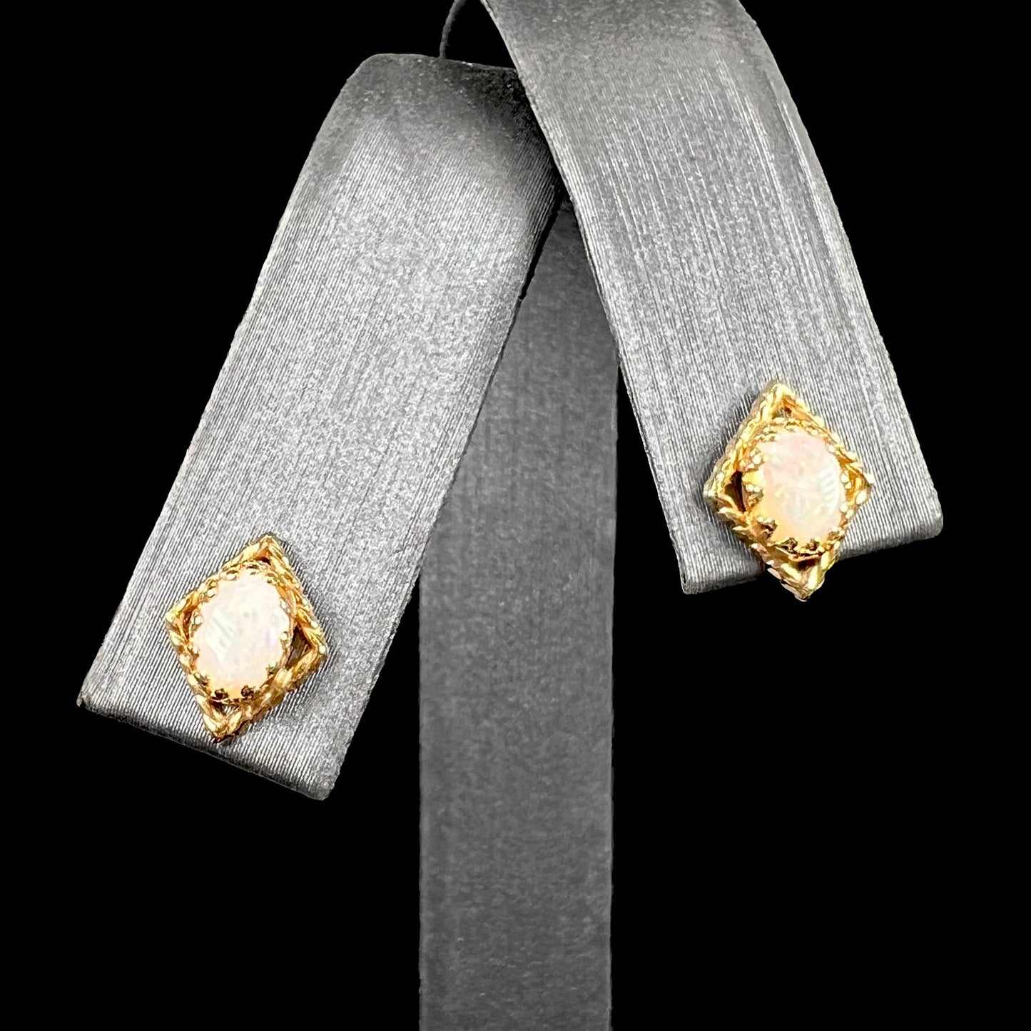 A pair of opal stud earrings. The opals are set in yellow gold diamond shaped mountings.
