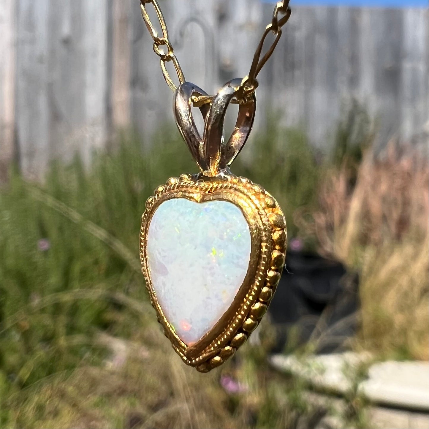 A yellow gold heart necklace mounted with a heart shaped white opal.