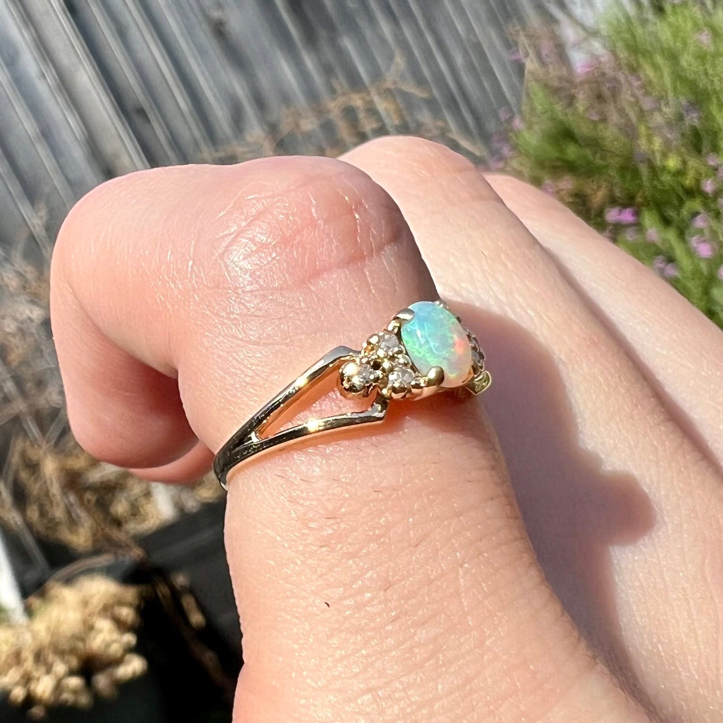 A ladies' yellow gold opal and diamond pinkie ring. The ring is a small size, and the opal shines green and blue colors.