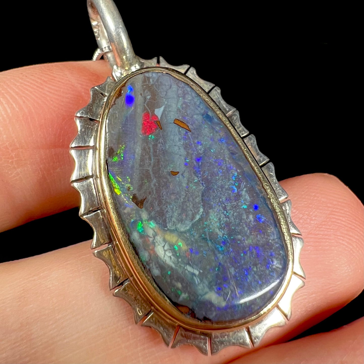 A Southwest style two-tone sterling silver pendant set with a black boulder opal with a yellow gold bezel.