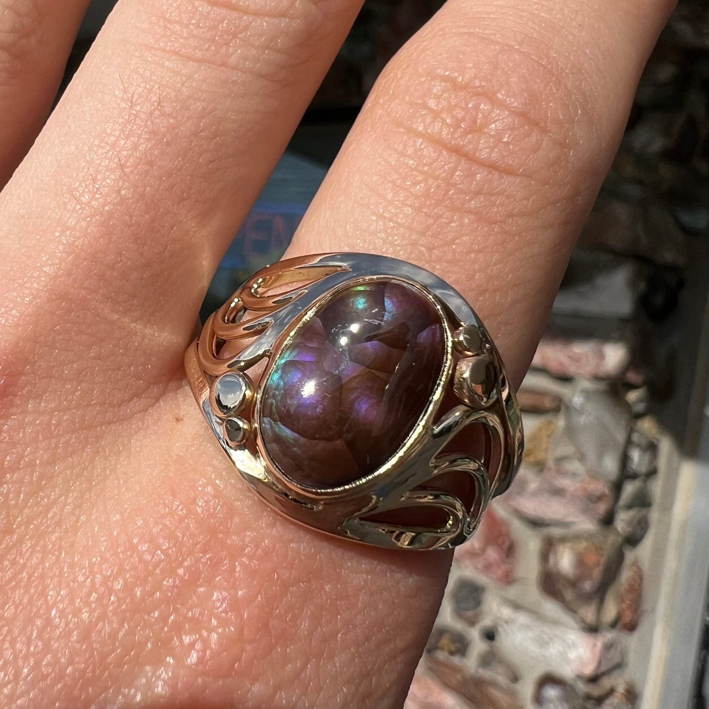 An oval cabochon cut fire agate with purple and blue colors set in a yellow gold men's ring.